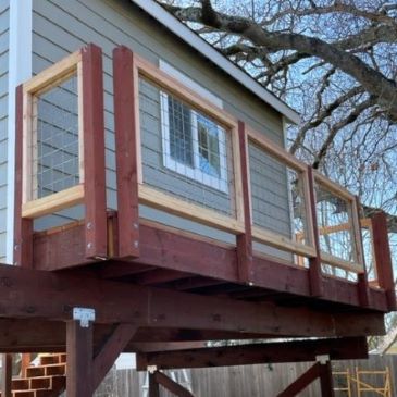Custom-built treehouse deck with a unique wooden frame and wire mesh railing.