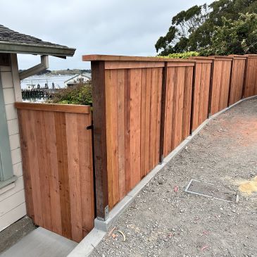 New privacy fence installation along a concrete footing with a view of Bodega Bay.